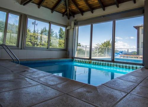 een zwembad in een huis met ramen bij Hermoso departamento frente al lago con piscina in Bariloche