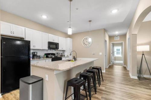 a kitchen with a black refrigerator and some bar stools at Sophisticated 3BD/2BA Retreat: Pool, Gym, Laundry in Melbourne