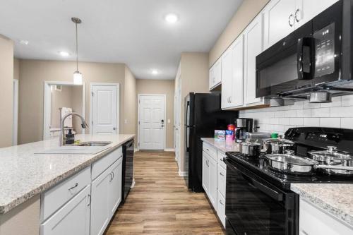 a kitchen with white cabinets and black appliances at Sophisticated 3BD/2BA Retreat: Pool, Gym, Laundry in Melbourne