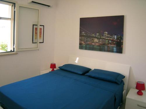 una camera con un letto blu e un dipinto sul muro di Villa Giulia Salento Mare a Torre Vado