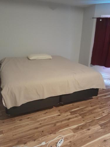 a bed in a bedroom with a wooden floor at Cozy place to rest in Hamilton