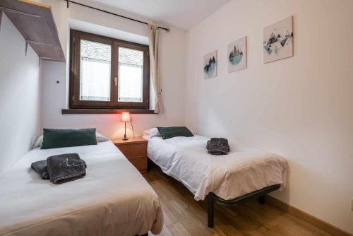a bedroom with two beds and a window at Prat deth Pas by SeaMount Rentals in Betrén