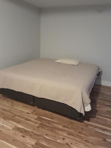 a bed in a white room with a wooden floor at Cozy place to rest in Hamilton