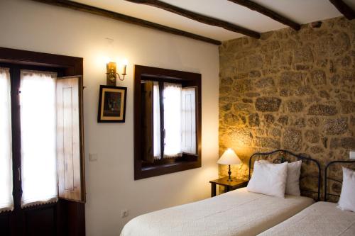 a bedroom with two beds and a stone wall at Casa d'Acha in São Miguel de Acha