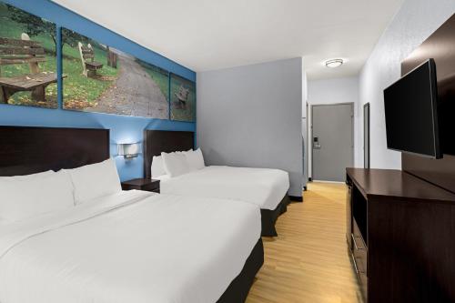 a hotel room with two beds and a flat screen tv at Clarion Pointe Hinesville near Fort Stewart in Hinesville