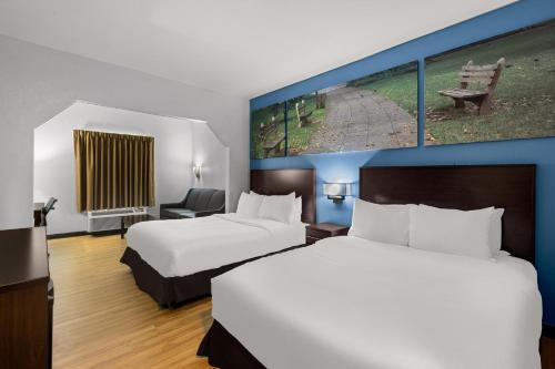 une chambre d'hôtel avec 2 lits et un tableau mural dans l'établissement Clarion Pointe Hinesville near Fort Stewart, à Hinesville