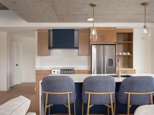 a kitchen with blue chairs and a counter top at Hôtel Expérience - Quartier Des Marinas in Magog-Orford