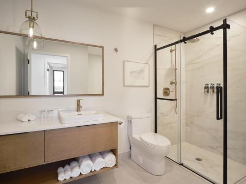 a bathroom with a shower and a toilet and a sink at Hôtel Expérience - Quartier Des Marinas in Magog-Orford