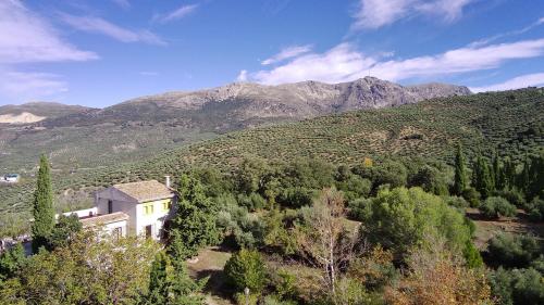 een huis op een heuvel met bergen op de achtergrond bij Finca Rural La Calderera in Valdepeñas de Jaén