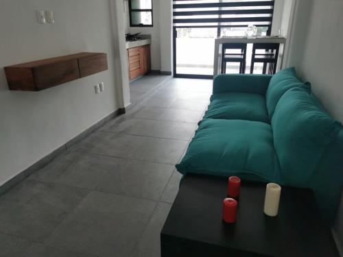 dept Miraflores في زيهواتانيجو: غرفة معيشة مع أريكة خضراء وطاولة