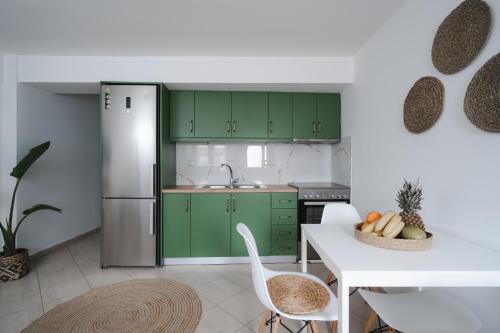 una cocina con armarios verdes y una mesa blanca en K-houses P, en Lefkada