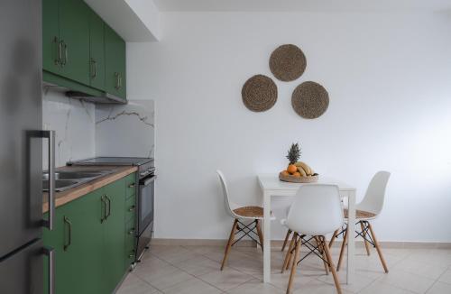 una cocina con armarios verdes, mesa y sillas en K-houses P, en Lefkada