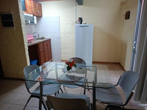 uma mesa de vidro numa cozinha com cadeiras e um frigorífico em Los Lirios de Dayman em Termas del Daymán