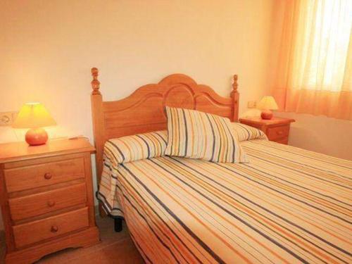 a bedroom with a bed with striped sheets and two lamps at Villa L'Ametlla de Mar, 5 pièces, 8 personnes - HISP-217-20 in L'Ametlla de Mar