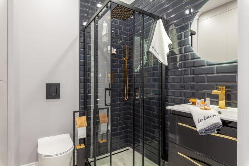 a bathroom with a glass shower and a sink at BOMBONIERKA Apartamenty in Krynica Zdrój