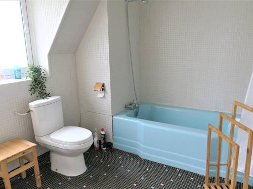 La salle de bains est pourvue de toilettes et d'une baignoire bleue. dans l'établissement Maison avec jardin clos à 800m de la plage à Trébeurden - FR-1-368-335, à Trébeurden