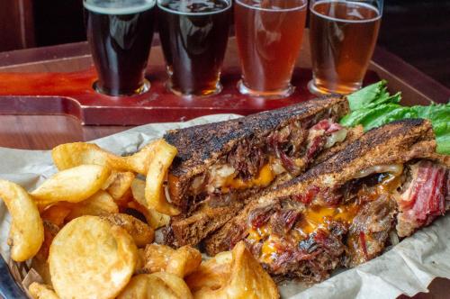 a sandwich and french fries on a tray with glasses of beer at Four Points by Sheraton Deadwood in Deadwood