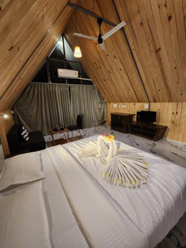uma grande cama branca num quarto com tectos em madeira em Nirved Retreat - A Backwater Forest Stay. 