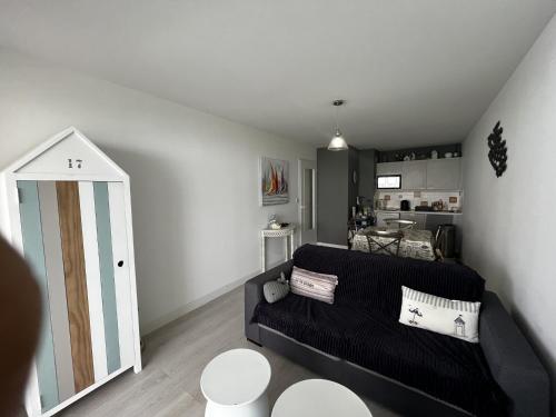 un salon avec un canapé noir et une cuisine dans l'établissement Appartement 3 pièces à 100m de la plage avec grande terrasse et WIFI – Les Sables-d'Olonne - FR-1-197-537, à Les Sables-dʼOlonne