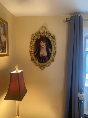 a painting of a woman on a wall with a lamp at Cozy room near Airport & Highway in Saint Louis