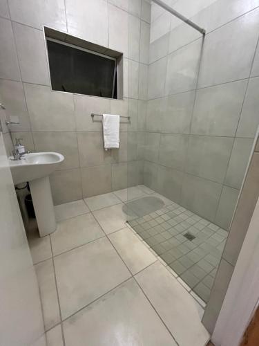 a white bathroom with a shower and a sink at Robridon in Summerstrand