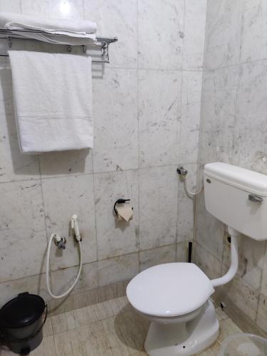 a bathroom with a white toilet and a towel at Unpack Hostel in Puducherry