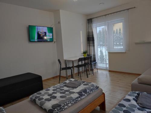 a living room with a table and a tv on the wall at Górski Kryształ in Stronie Śląskie