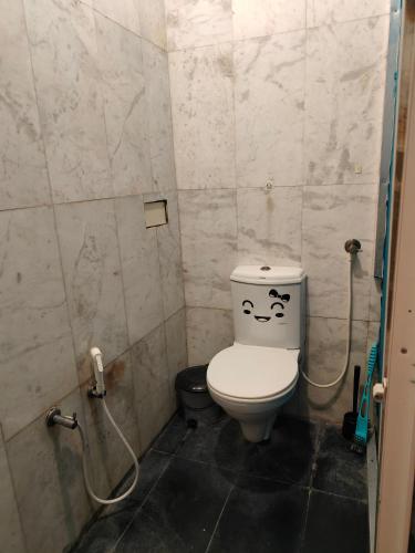 a small bathroom with a toilet with a face drawn on it at Unpack Hostel in Puducherry
