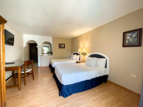 a hotel room with two beds and a desk at Hotel Gran Plaza & Convention Center in Guanajuato