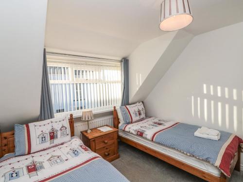 a bedroom with two beds and a window at Avon Croft Cottage in Hawsker