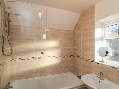 a bathroom with a shower and a tub and a sink at Avon Croft Cottage in Hawsker