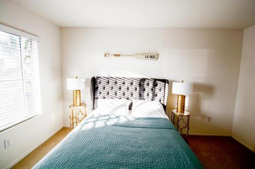 a bedroom with a bed with a green blanket and two lamps at Bay Views & Gaslamp/Little Italy/Convention 1BD in San Diego