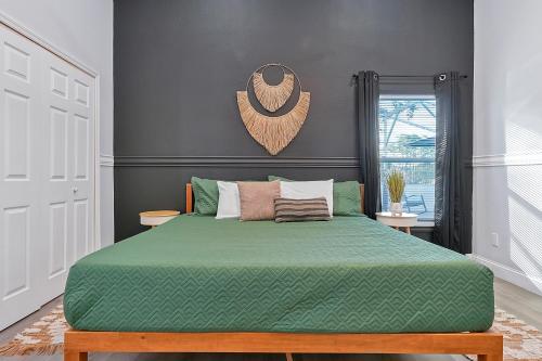 ein Schlafzimmer mit einem Bett mit einer grünen Bettdecke in der Unterkunft Your Family Fun Villa w Pool, Game room, all you need, close to Disney & more in Davenport