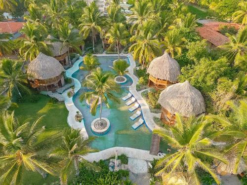 an aerial view of a resort swimming pool with palm trees at Hotel Tortuga Village in La Herradura