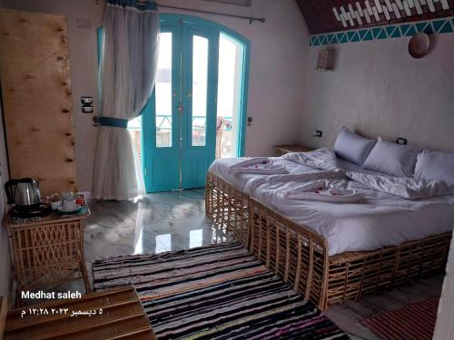 sypialnia z dużym łóżkiem i niebieskimi drzwiami w obiekcie Miskaa Nubian House w mieście Naj‘ Tinjār