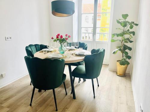 a dining room table with green chairs and a table and chairsktop at FILMAP-Apartments-Zentrale Lage-Boxspringbett-Beamer-Popcorn-gratis Parkplatz in Görlitz