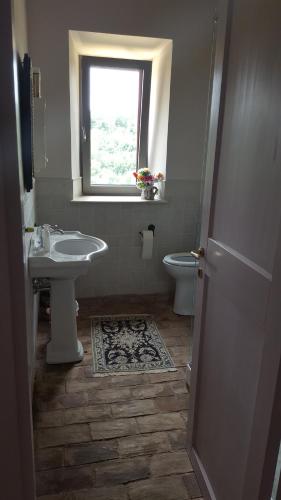 łazienka z umywalką, toaletą i oknem w obiekcie Villa Primavera w mieście Stimigliano