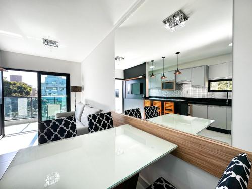 cocina abierta y sala de estar con mesa blanca en Bombinhas Monserrate, en Bombinhas