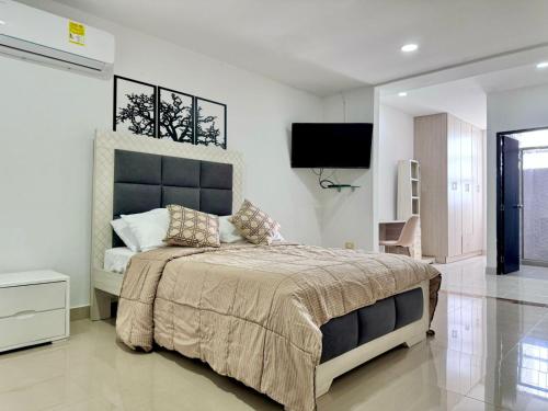 ein Schlafzimmer mit einem großen Bett und einem Flachbild-TV in der Unterkunft HELENE HOUSE in Sincelejo
