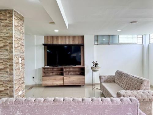 a living room with a couch and a flat screen tv at HELENE HOUSE in Sincelejo