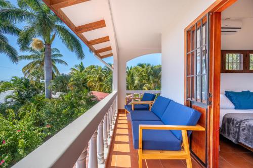 a balcony with blue chairs and a bed and palm trees at Casa Palma Real in Playa Junquillal