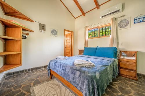 a bedroom with a bed with blue sheets and a window at Casa Palma Real in Playa Junquillal
