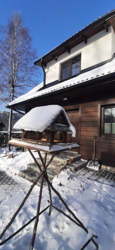 a snow covered table in front of a house at Chatička pod Lysou in Ostravice