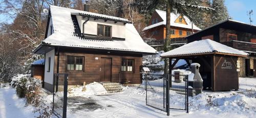 een klein houten huis met sneeuw op het dak bij Chatička pod Lysou in Ostravice