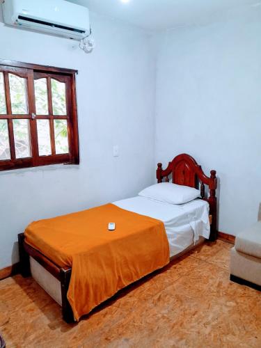 um quarto com uma cama com um cobertor laranja em Departamento em Maco