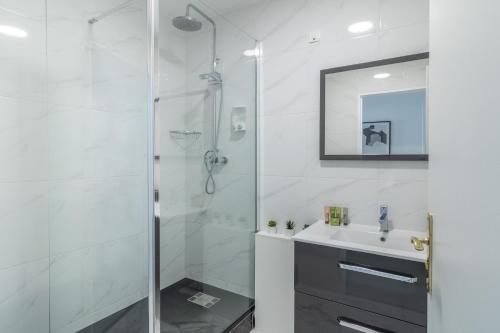 een witte badkamer met een douche en een wastafel bij L'Évasion Bleue à Disneyland Paris - 6 personnes in Chessy