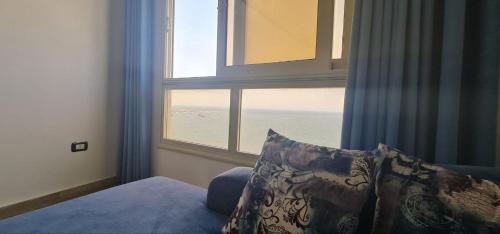 1 dormitorio con ventana y vistas al océano en شقة فاخرة مكيفة تري البحر مباشرة, en Alejandría