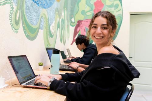 a woman sitting at a desk working on her laptop at UCO Live Roma in Mexico City