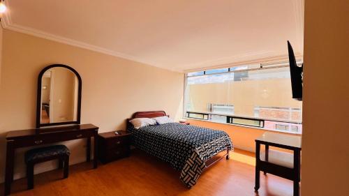 um quarto com uma cama, um espelho e uma janela em Departamento de lujo 2 habitaciones, 2 baños, wifi, parqueadero, República de El Salvador em Quito