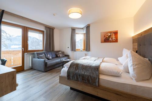 a bedroom with a bed and a couch in a room at Hotel Thuinerwaldele in Vipiteno